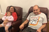 Grandmother pictured sitting with granddaughter and son in brown leather armchairs.