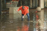 A man in an orange jacket cleaning up flood water