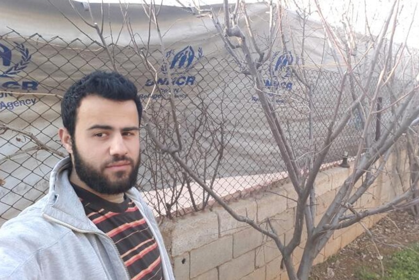 Mohammad Darwish stands next to a fence.