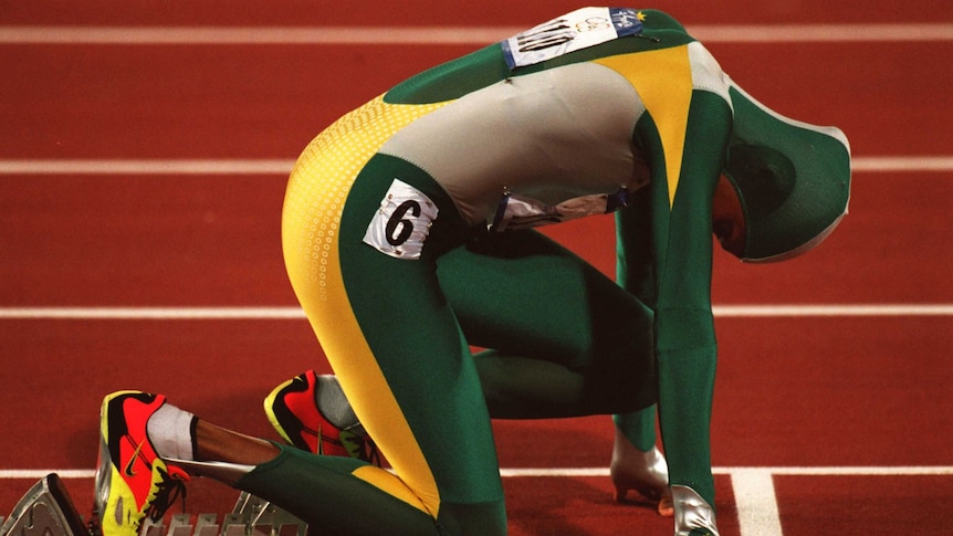 Cathy Freeman on the starting blocks at the 400m final Sydney Olympic Games 2000, wearing a green, gold and grey full body suit