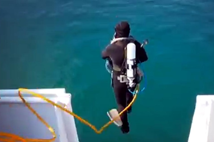 A pearl diver jumps into the water from a ship.