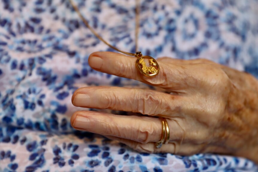 close up of old hand showing a golden pendant 