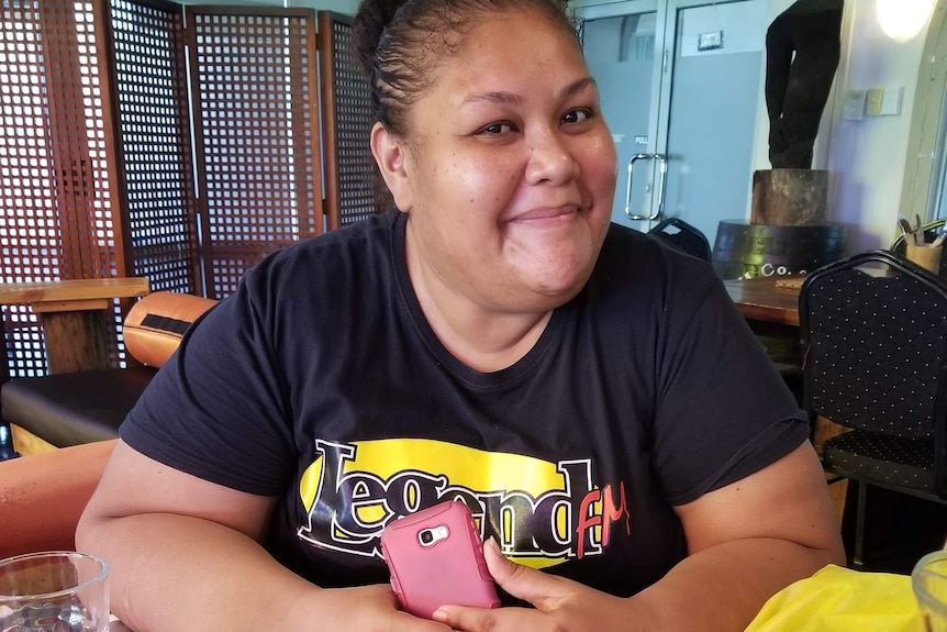 A photo of a woman wearing a T-shirt with her radio station on it. 