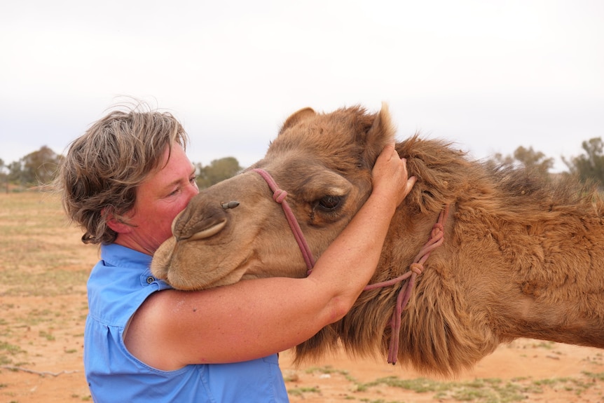 A woman hugging a camel.