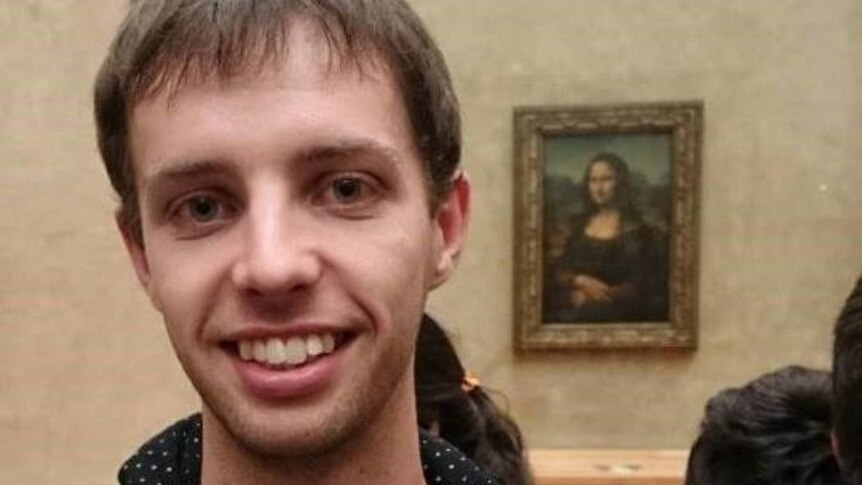 A man smiling in front of the Mona Lisa