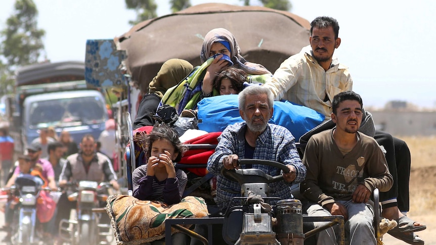 Internally displaced people from Deraa, Syria drive on a tractor