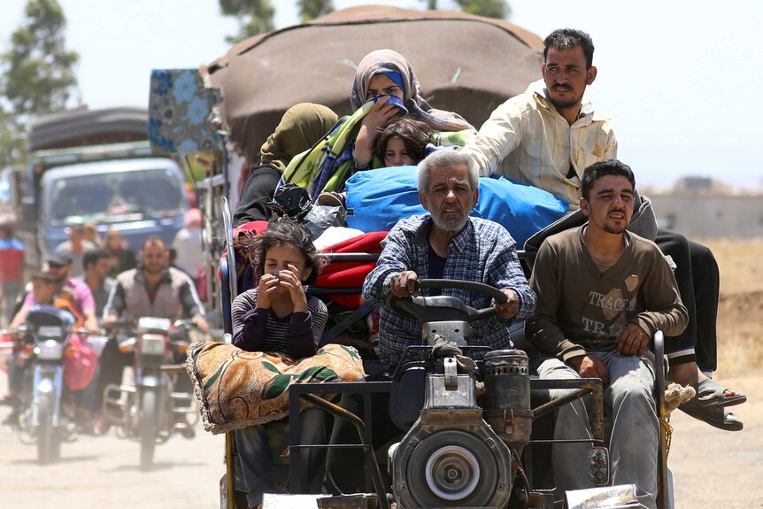 Internally displaced people from Deraa, Syria drive on a tractor