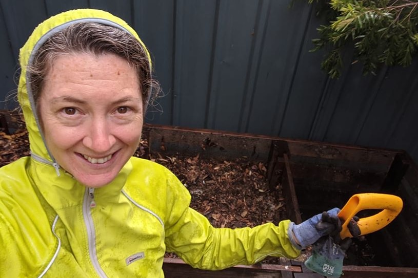 Brook Clinton standing in front of some compost piles, smiling.