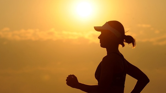 Picture of woman jogging against the backdrop of a rising sun
