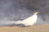 Plane waterbombs a bushfire at Frazerview, west of Kalbar, on Queensland's Scenic Rim