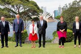 Australian and UK ministers stand on a grassed area overlooking the Sydney Opera House