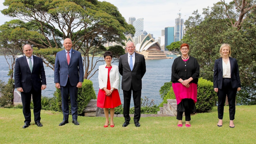 Australian and UK ministers stand on a grassed area overlooking the Sydney Opera House