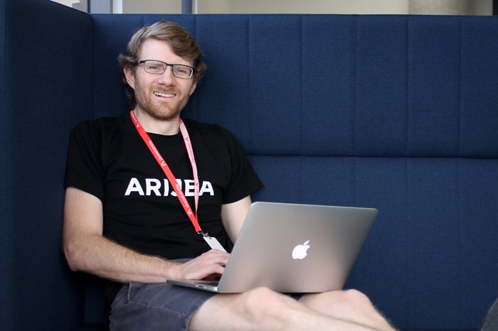 Nicholas Muldoon sits on a couch with his laptop computer.