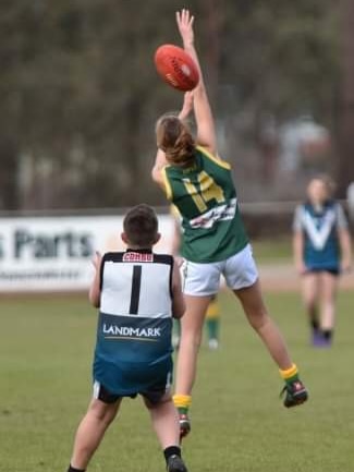 A young girl leaps for the football.