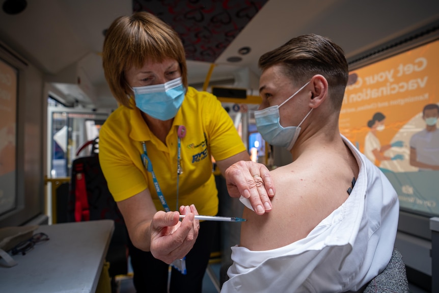 A young office workers gets his jab in a mobile vaccine bus in inner London.