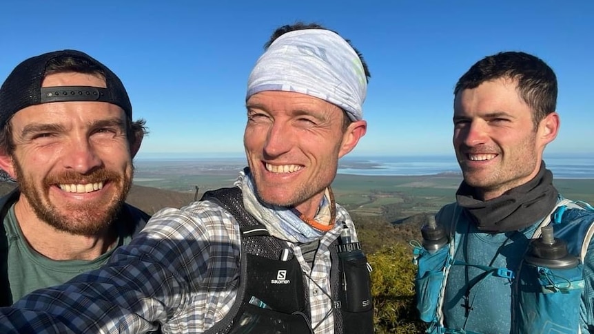 Three men take smiling selfie