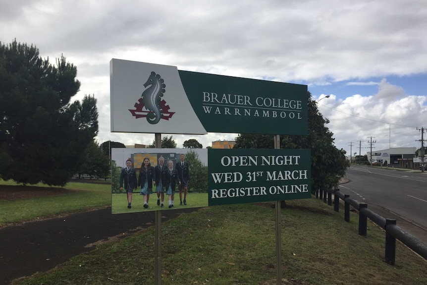 A sign for a school called Brauer College, beneath a cloudy sky in the country.