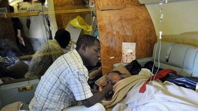 Bahia Bakari lies in a stretcher next to her father in a plane July 2, 2009 (Stephane De Sakutin, AFP)