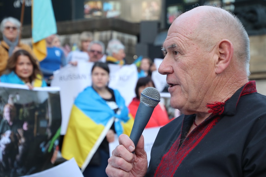 A man speaks into a microphone at a rally for Ukraine