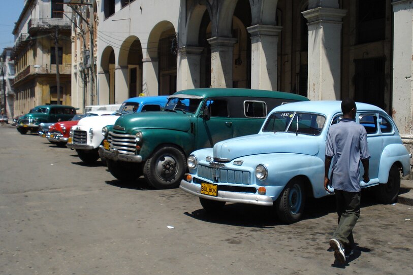 A man walks by a line of cars in the Cuban capital of Havana.