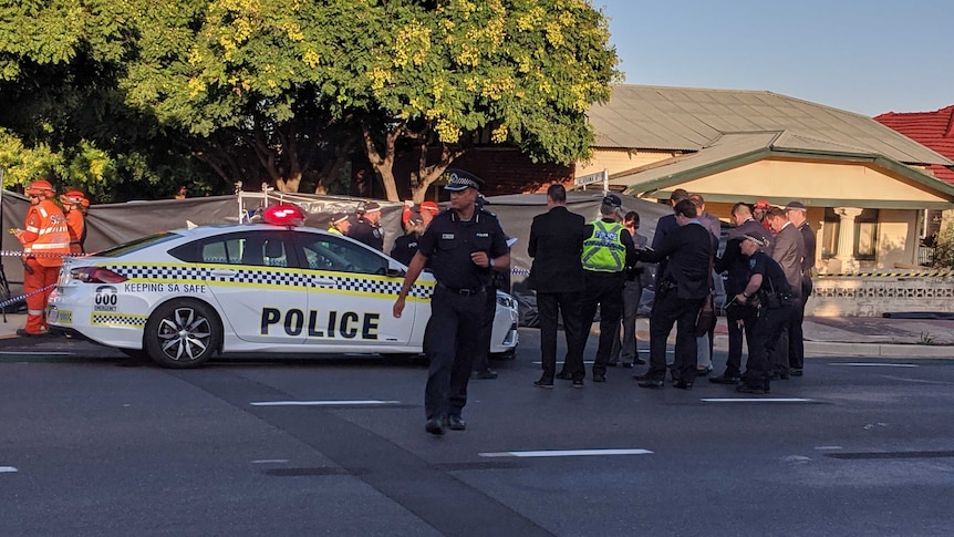 Police officers and a police car on a road in front of a house