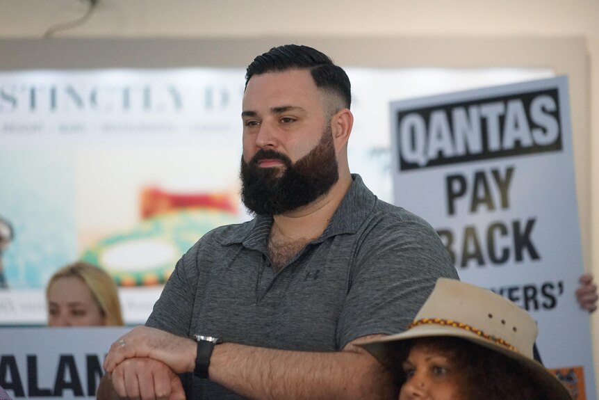 A tall man with a dark-haired beard standing at a protest