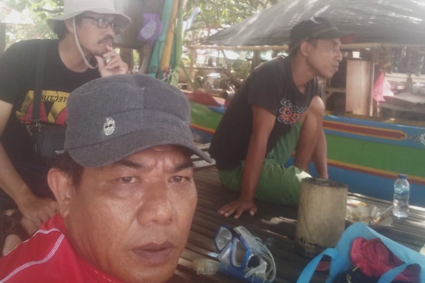 A selfie of a man at the front with two men at the back not facing camera.