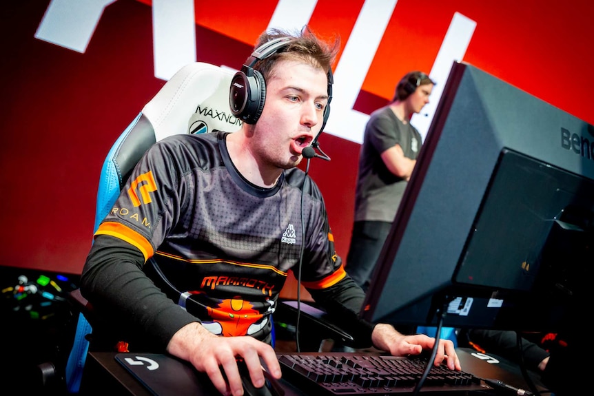 A Mammoth team member talks through headphones while playing a game with a keyboard and mouse at the Melbourne Esports Open.