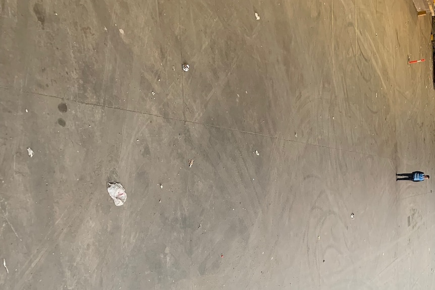 A man stands in a large, concrete space showing where stockpiles of waste used to be.