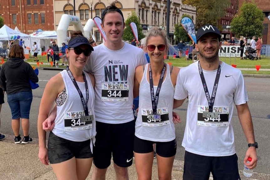 Four people in white shirts posing after completing a marathon