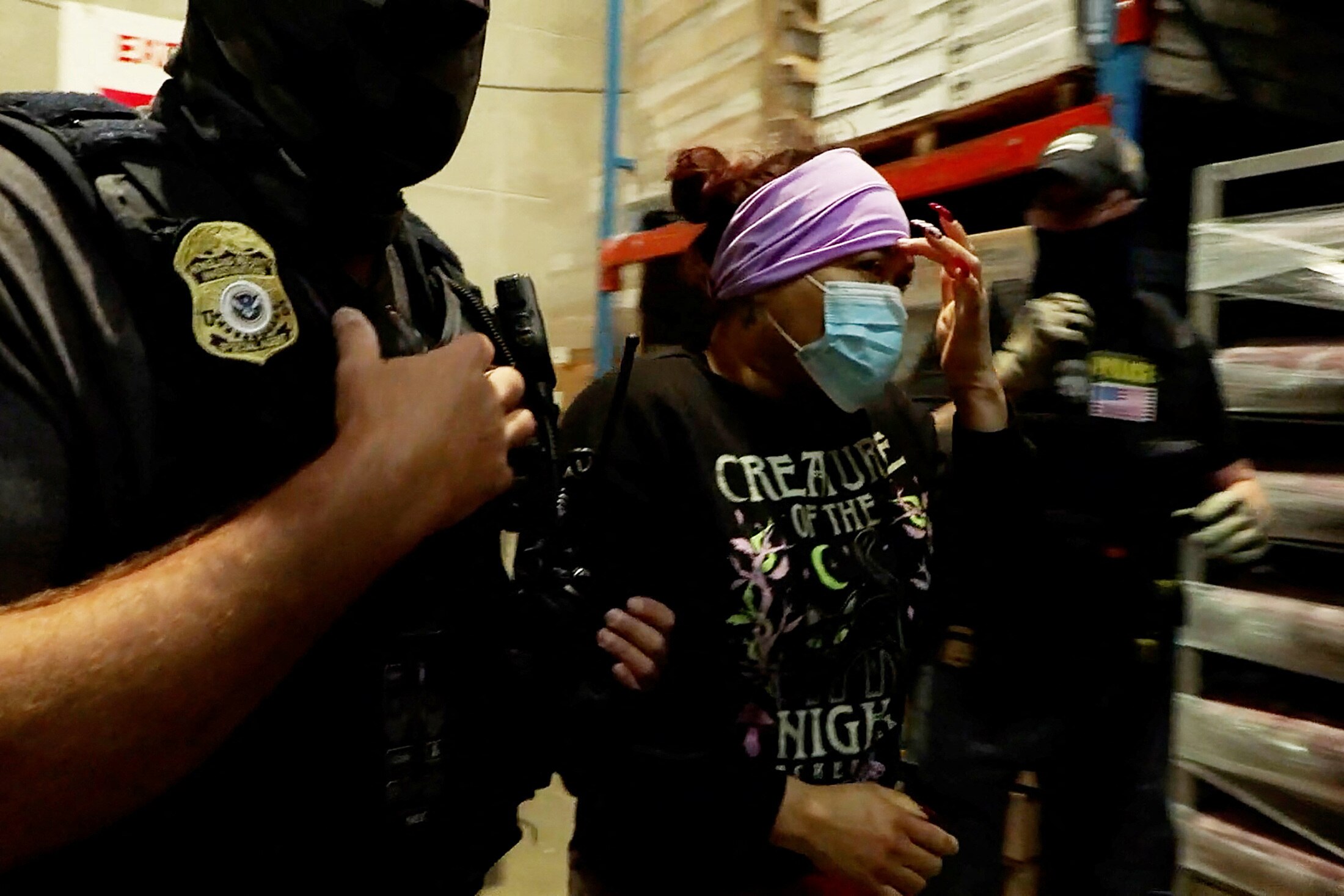 A woman is detained by US ice officials at a food production plant