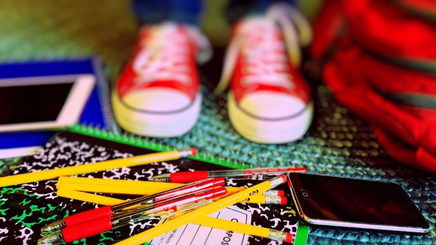 Pens and pencils sit at a student's feet.