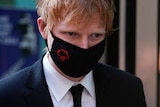 A close up of Ed Sheeran wearing a black face mask 