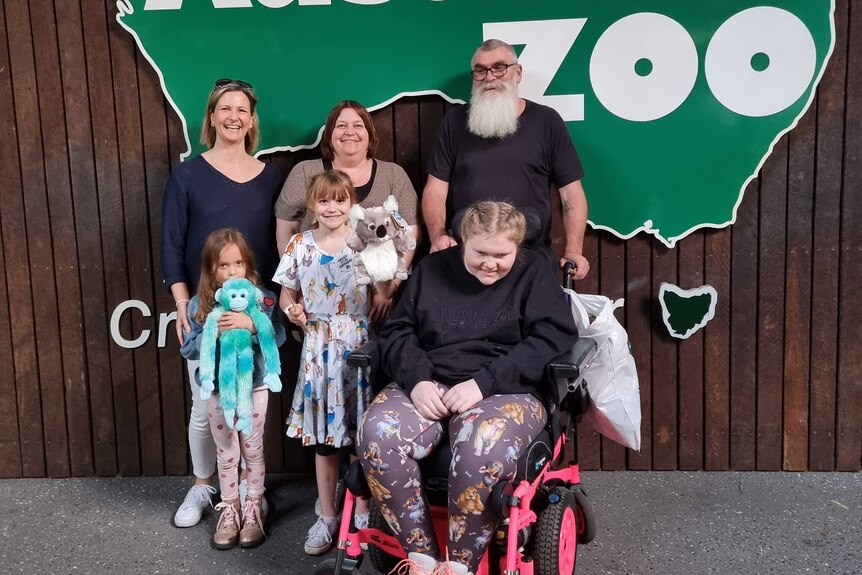 A group of people stand in front of a sign that says zoo
