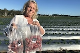 Mandy Schultz with the frozen strawberries standing in front of a field.