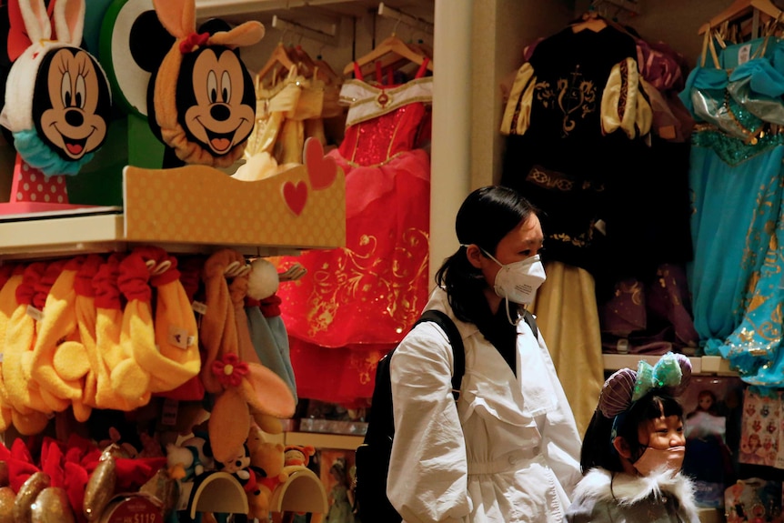 A child wears mask as she tries a themed ears at a souvenir shop in Disneyland hotel  in Hong Kong.