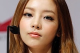 A close up of a South Korean female K-pop star with a microphone in front of her