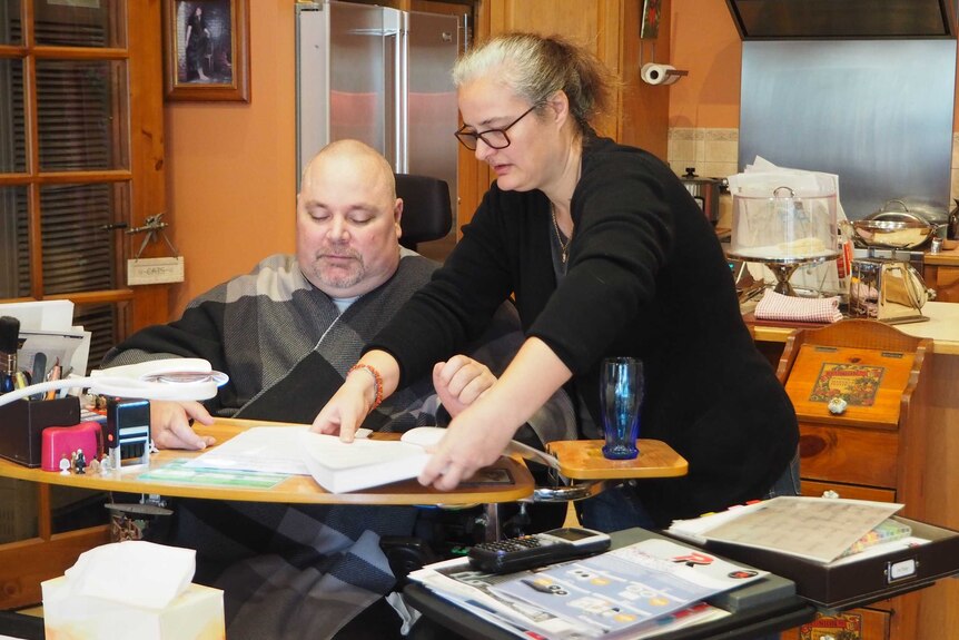 A woman provides care to a man with tetraplegia.