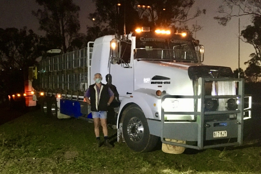 Rex Carruthers stands next to his fully loaded truck wearing a mask.