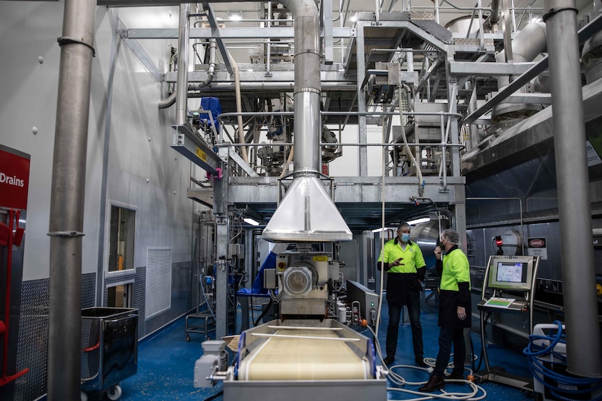 A large steel machine inside of a food production factory.