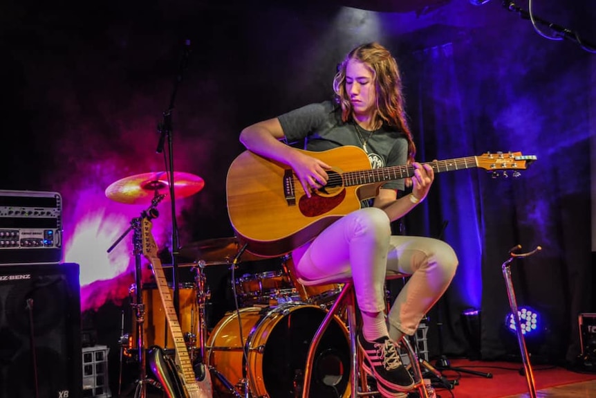 Young woman on stage playing guitar  