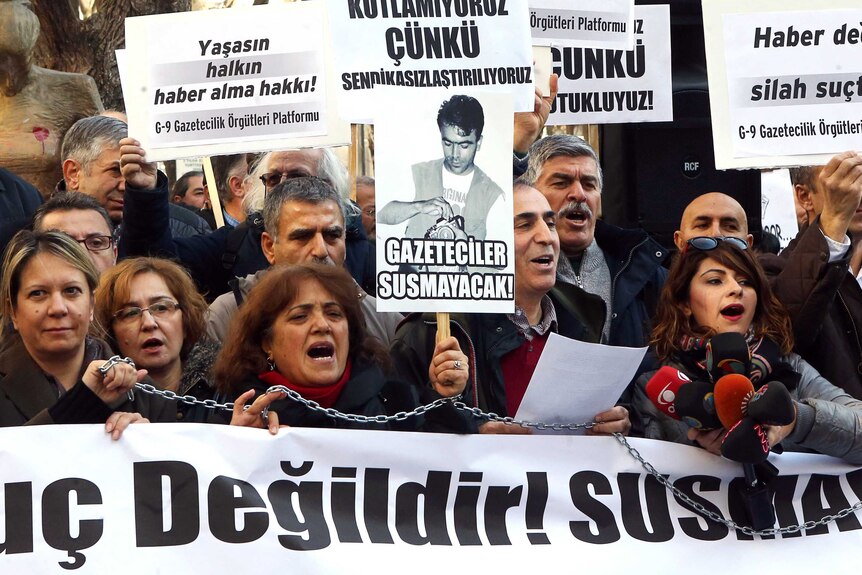 Turkish journalists hold banners and shout slogans during a demonstration in support of the charged journalists.