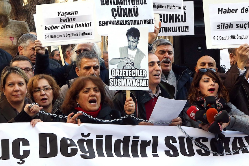 Turkish journalists hold banners and shout slogans during a demonstration in support of the charged journalists.