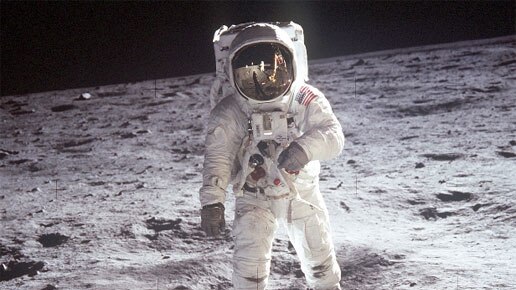 An astronaut in a special suit, walks across the grey surface of the Moon