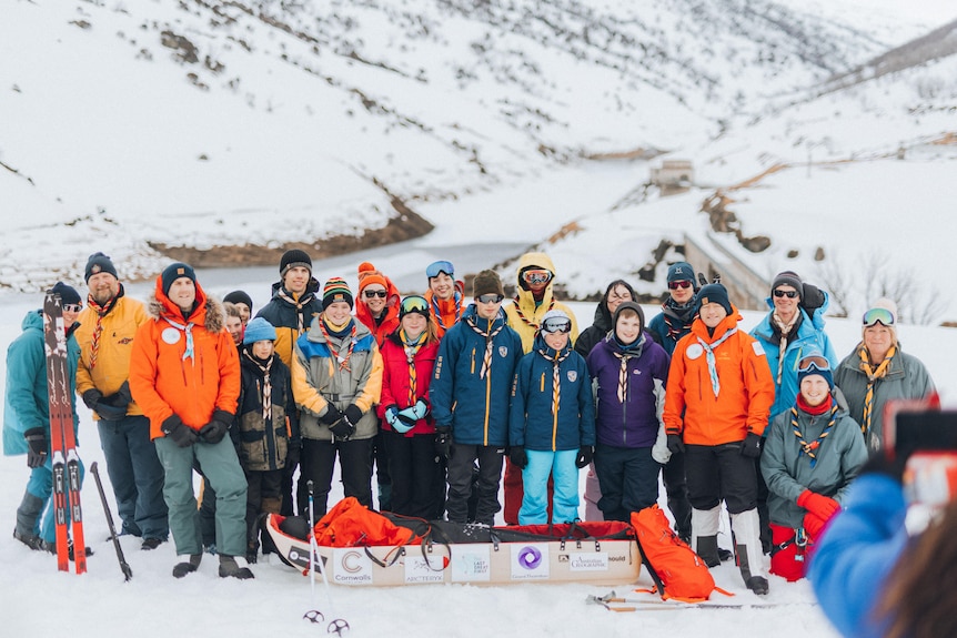 A group of young children in the snow smiling at the camera. 