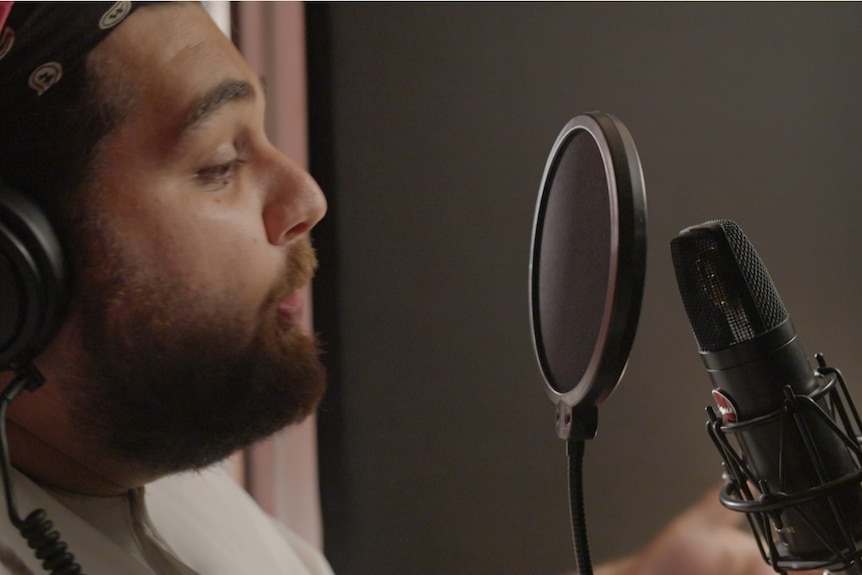 Man with beard sings into microphone