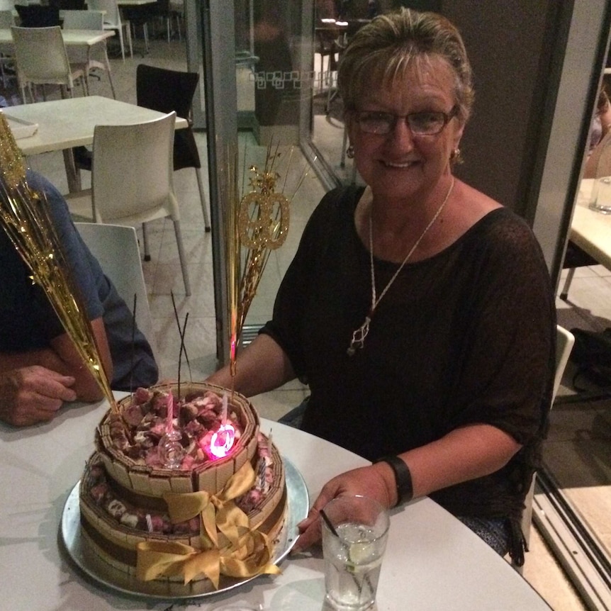 Joy Price sitting at a table with a birthday cake.