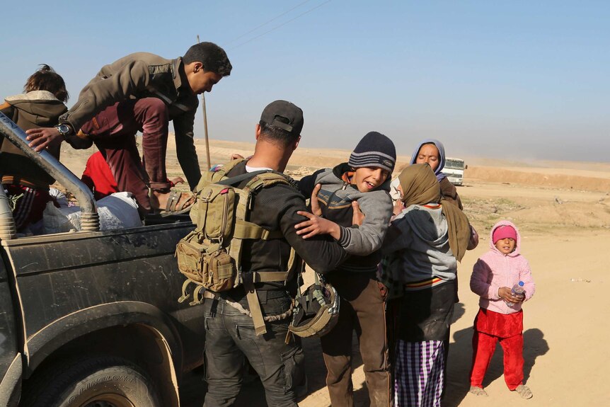 Displaced Iraqis from Mosul's west, mostly women and children, climb out a truck after being transferred out of the city.