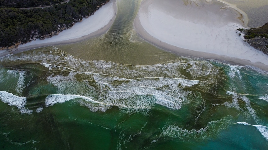 An aerial view of a river meeting the sea.