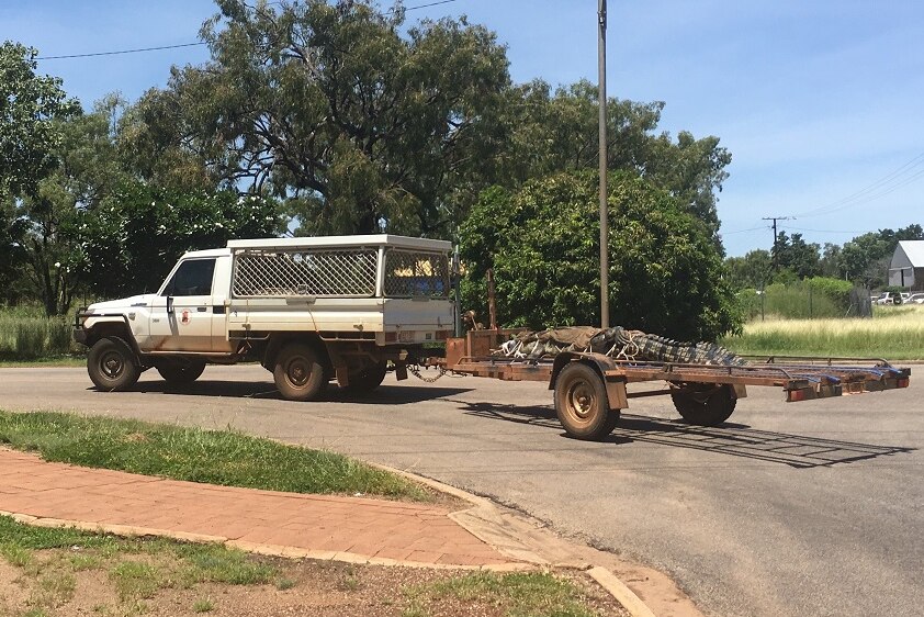 A car drives through town with a 3.92 metre crocodile strapped to the back trailer.